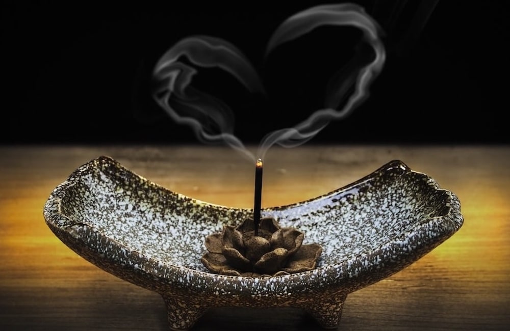 Incense in a burner with heart-shaped smoke